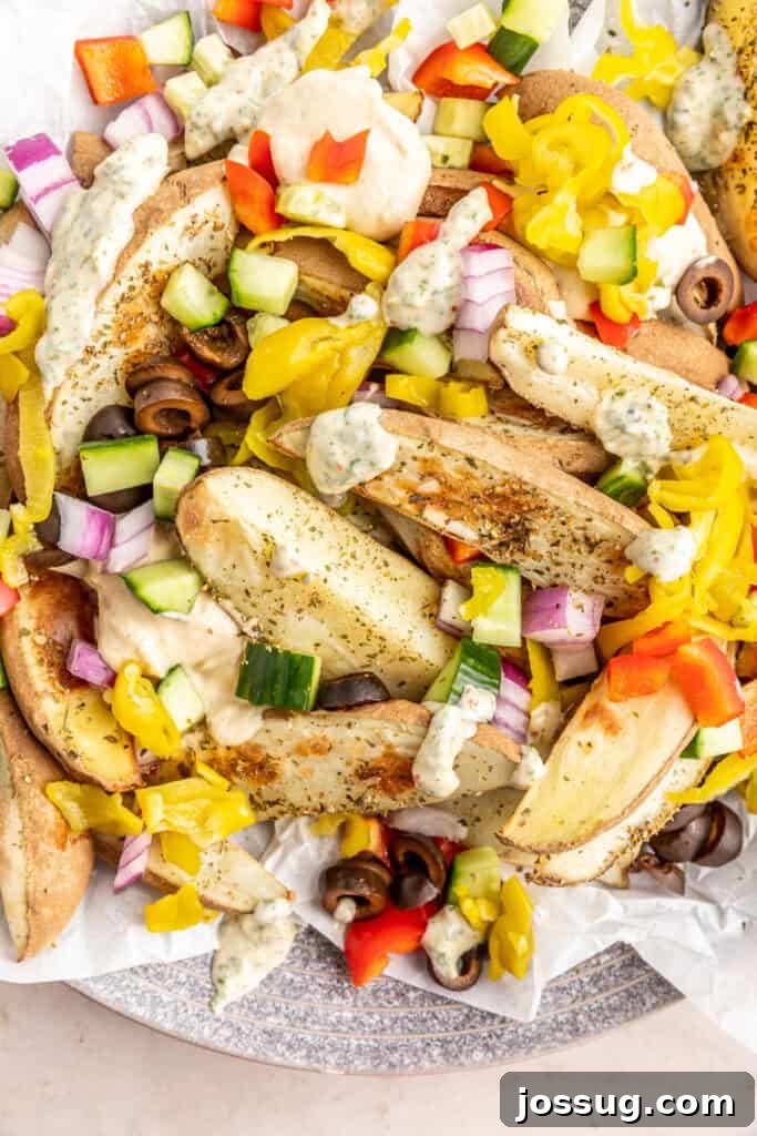Mediterranean Potato Wedge Feast 2 Extreme close-up of golden brown potato wedges topped with baba ganoush, a drizzle of creamy herb sauce, and a colorful mix of diced tomatoes, cucumbers, black olives, red onions, and banana peppers, showcasing the rich Mediterranean toppings.
