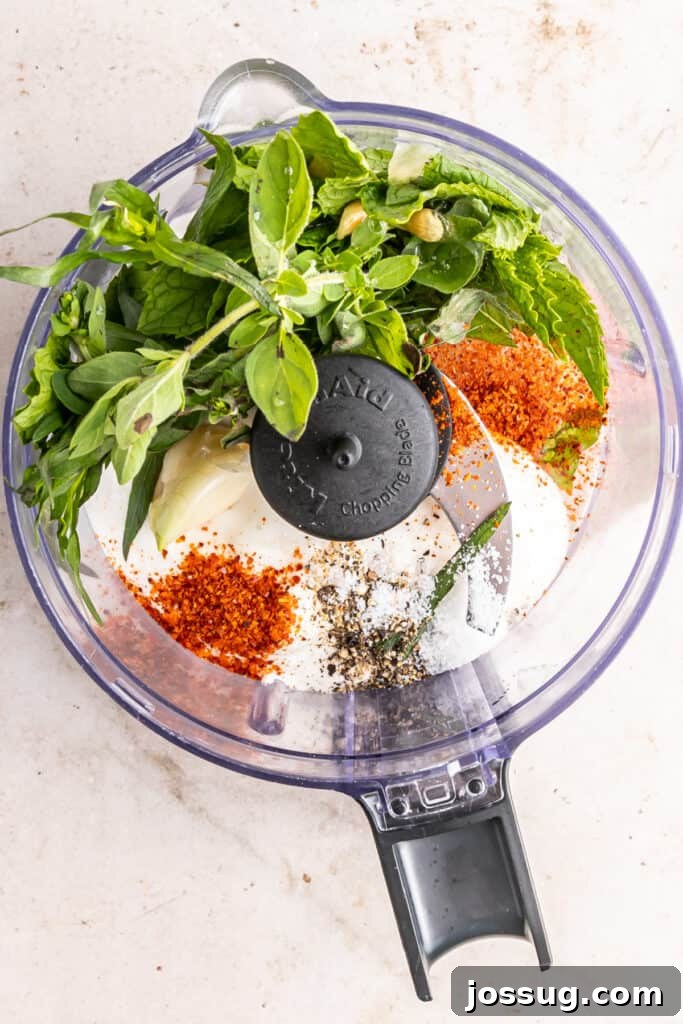 Mediterranean Potato Wedge Feast 5 Ingredients for creamy herb sauce in a food processor, including yogurt, fresh herbs, garlic, and seasonings, ready to be blended.