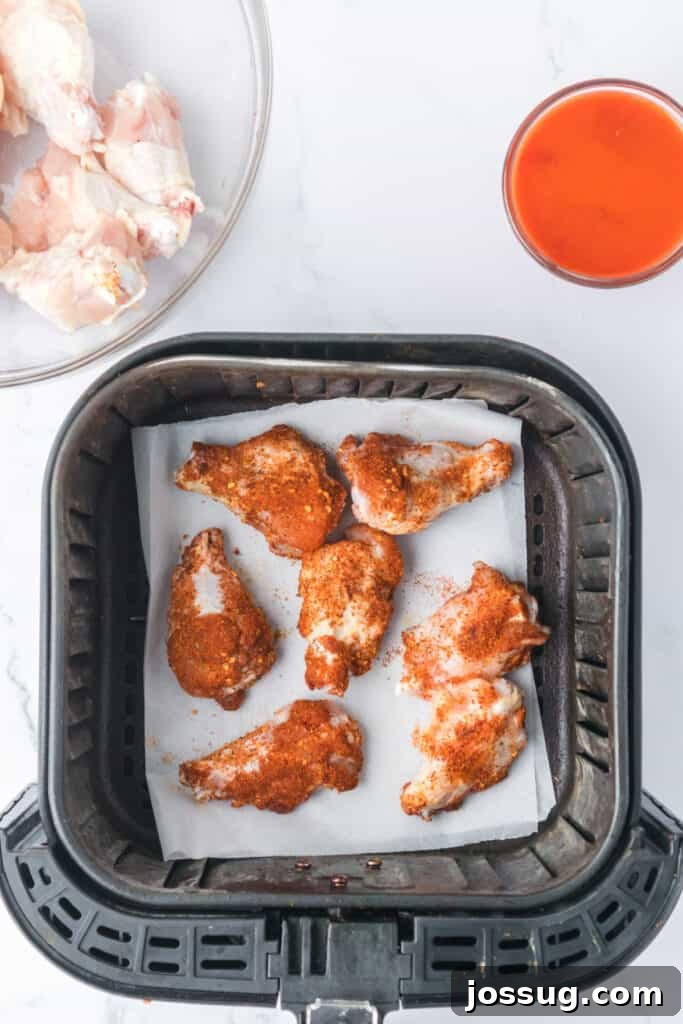 Perfectly Crispy Air Fryer Buffalo Wings 5 Uncooked seasoned chicken wings placed in an air fryer basket