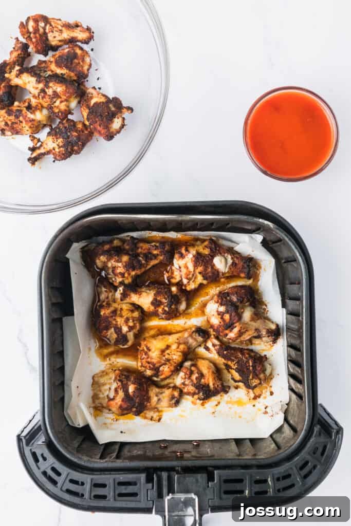 Perfectly Crispy Air Fryer Buffalo Wings 6 Cooked seasoned chicken wings in an air fryer basket, perfectly golden