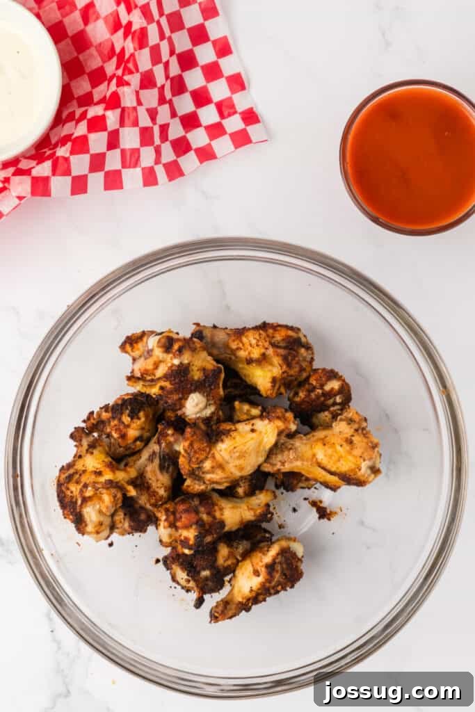 Perfectly Crispy Air Fryer Buffalo Wings 7 Cooked seasoned wings in a mixing bowl, ready for sauce