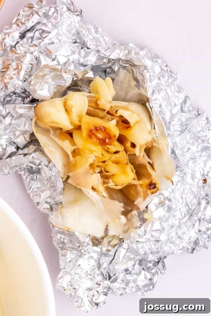 Preheat your air fryer to 390°F (200°C). Cut off the top of the head of garlic and drizzle it with olive oil (1 teaspoon). Wrap it tightly in aluminum foil. Place the wrapped garlic directly in the air fryer basket and cook for 25 minutes or until the cloves are soft when pressed and lightly golden brown.