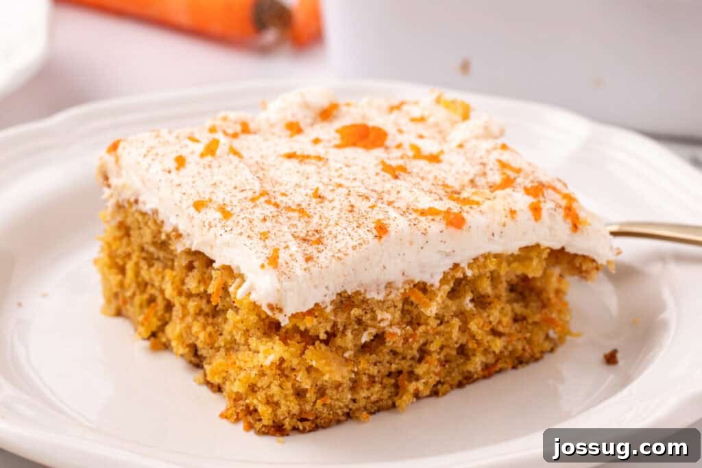 A generous slice of carrot sheet cake with thick cream cheese frosting, garnished with a sprinkle of cinnamon, served on a rustic plate