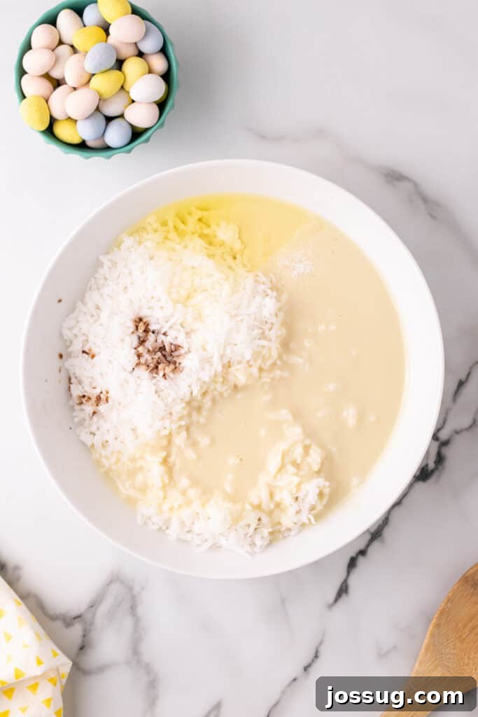 Flake coconut, sweetened condensed milk, egg white, vanilla extract, and salt are combined in a large mixing bowl, ready to be blended into the dough for coconut Easter nests.