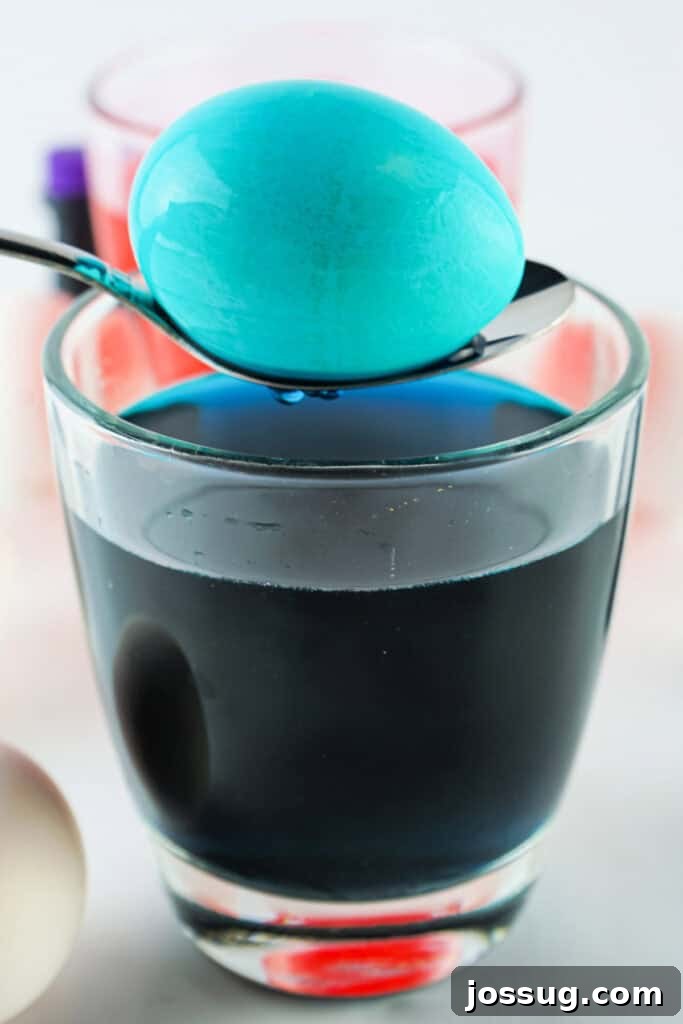 A freshly colored Easter egg held on a spoon after being removed from dye