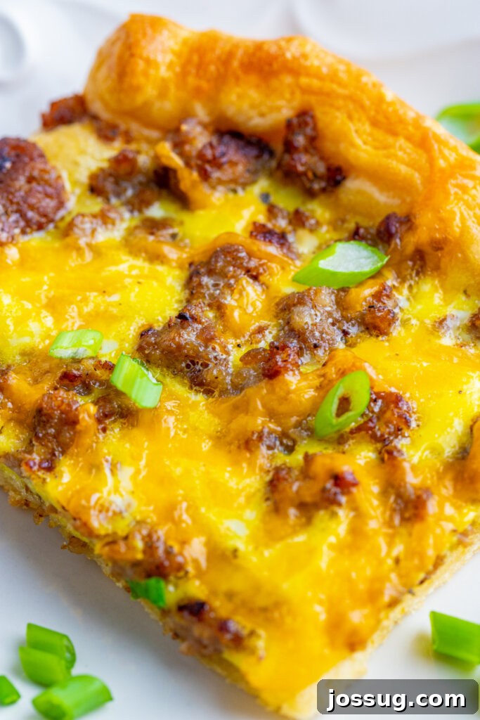 Delicious breakfast pizza made with flaky crescent rolls, topped with eggs, cheese, and breakfast meats
