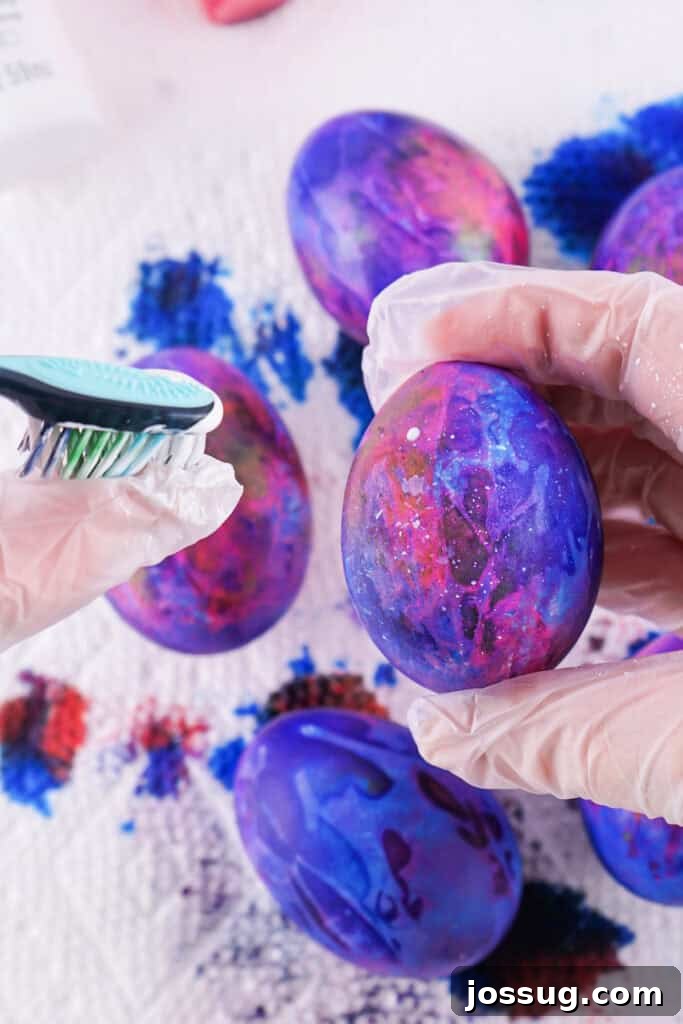 Cosmic Curiosities Uncovered 7 A toothbrush being used to flick white paint onto a dyed egg, creating a splatter effect.