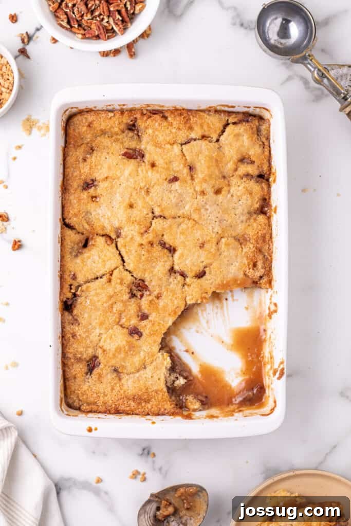 Decadent Pecan Cobbler 8 Pecan pie cobbler in baking dish with scoop taken out of the cobbler