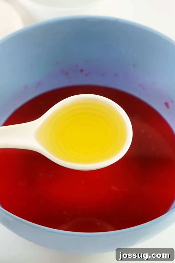 Adding cooking oil to the colored water mixture, showing oil droplets on the surface