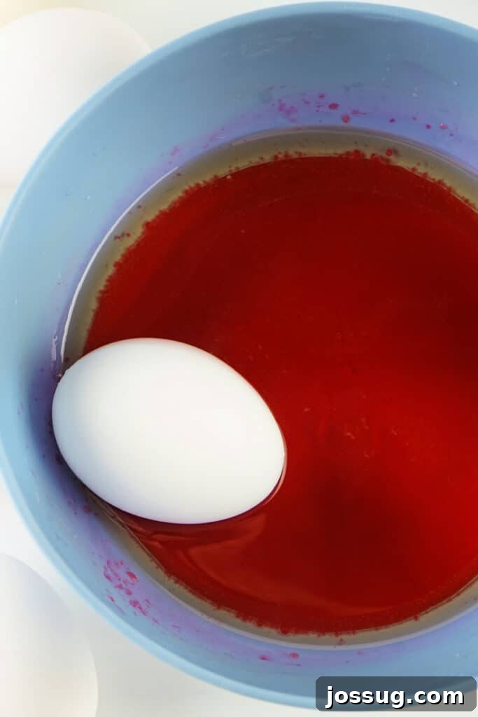A hard-boiled egg being dipped into the dye and oil mixture, ready for marbling
