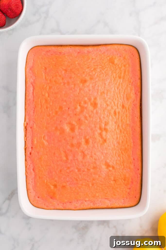 A perfectly baked strawberry cake, golden-brown around the edges, still in its 9x13 inch baking dish, cooling down.