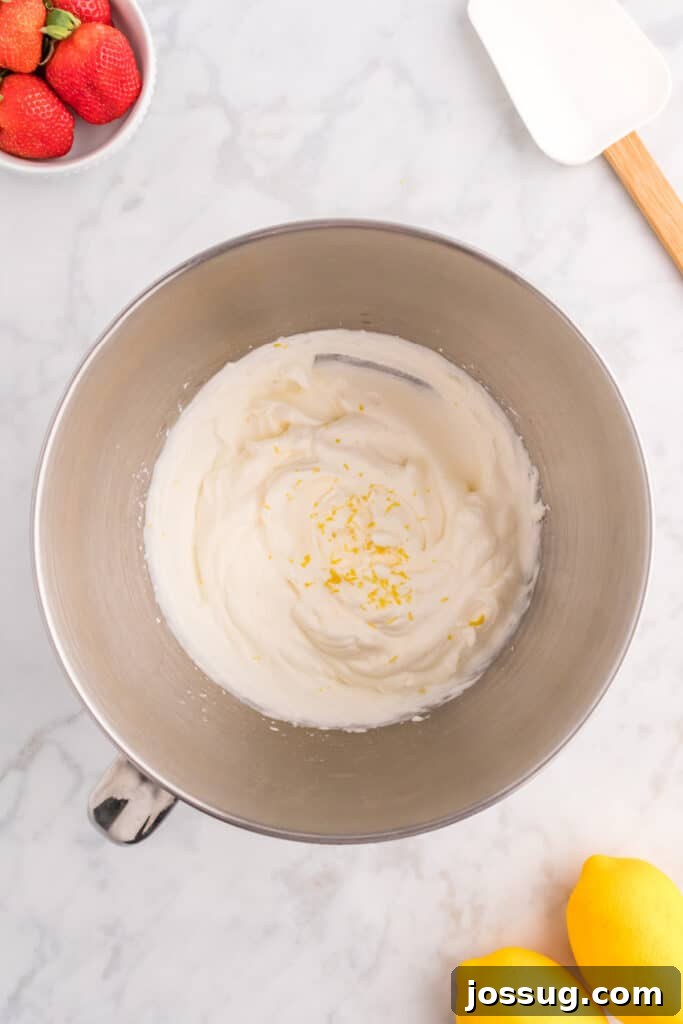 Fluffy, pale yellow lemon cream topping in a mixing bowl, showing its light and airy texture after whipping.