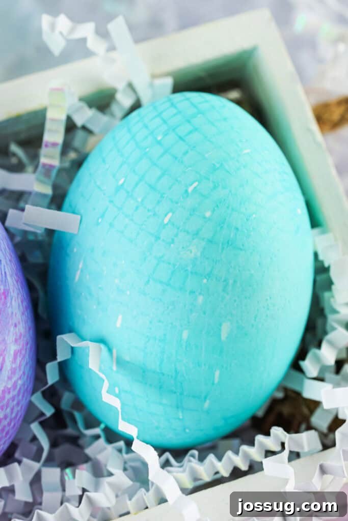 Textile Art Easter Eggs 2 Closeup of a teal fabric textured Easter egg in a wooden box, showcasing intricate lace patterns.