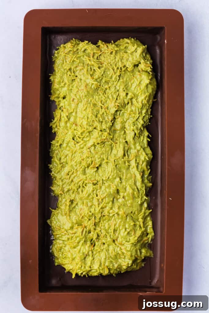 Golden Dubai Delight 12 Filled chocolate bar mold with the green pistachio-kataifi-tahini mixture spread in the center.