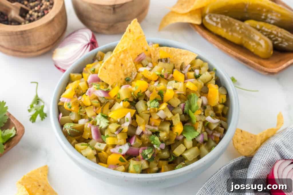 A bowl of Pickle de Gallo with tortilla chips, surrounded by ingredients like red onion, pickles, and spices.