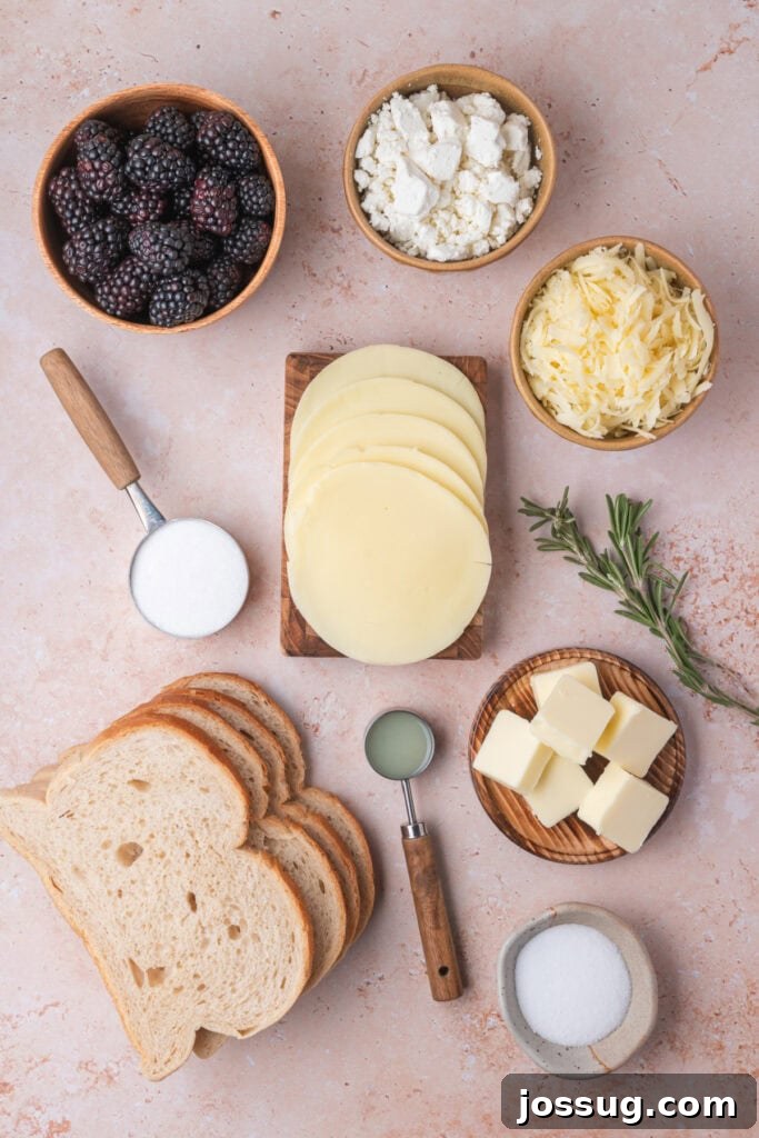 Sweet and Savory Blackberry Grilled Cheese 3 Flat lay of all fresh ingredients for blackberry grilled cheese, including vibrant blackberries, various cheeses, butter, rosemary, sugar, and sourdough bread