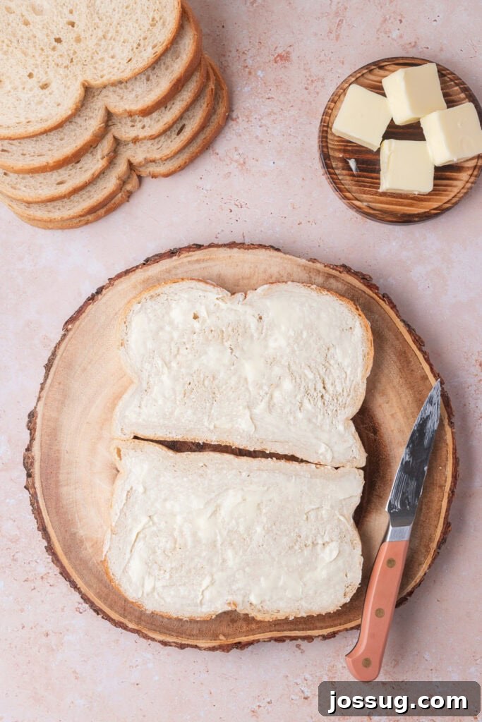 Sweet and Savory Blackberry Grilled Cheese 6 Slices of sourdough bread evenly spread with butter, stacked beside a wooden plate with butter cubes