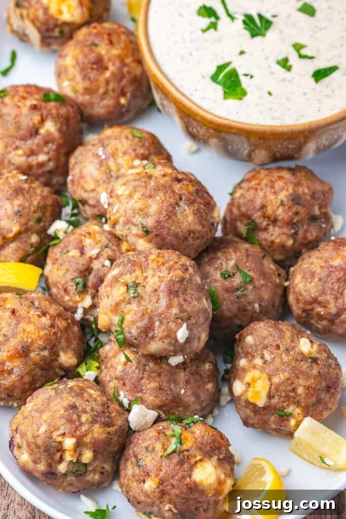 Closeup of plated turkey feta meatballs with lemon wedges and dipping sauce