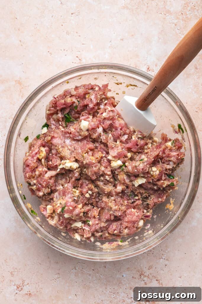 Mixed turkey meatball mixture in a glass bowl with spatula ready for scooping
