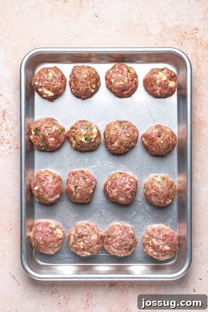 Raw turkey feta meatballs shaped and placed evenly on a baking sheet