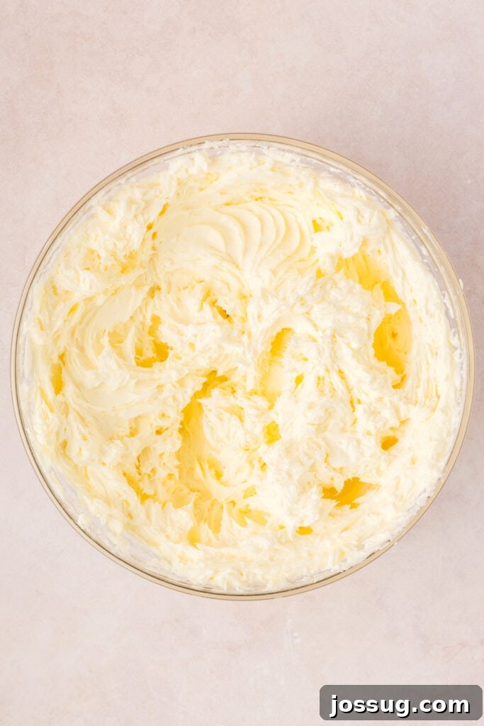 Bowl of whipped cream cheese and sugar mixture for the cheesecake filling, showing a light and fluffy consistency