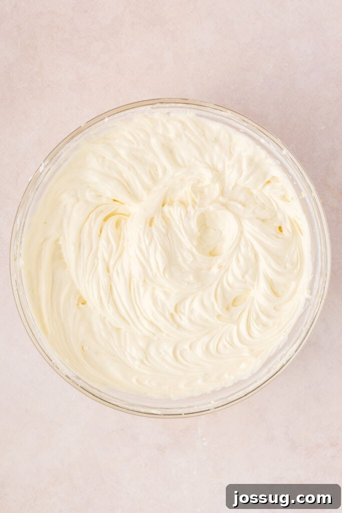 Creamy cheesecake filling being mixed until smooth with a spatula in a large bowl