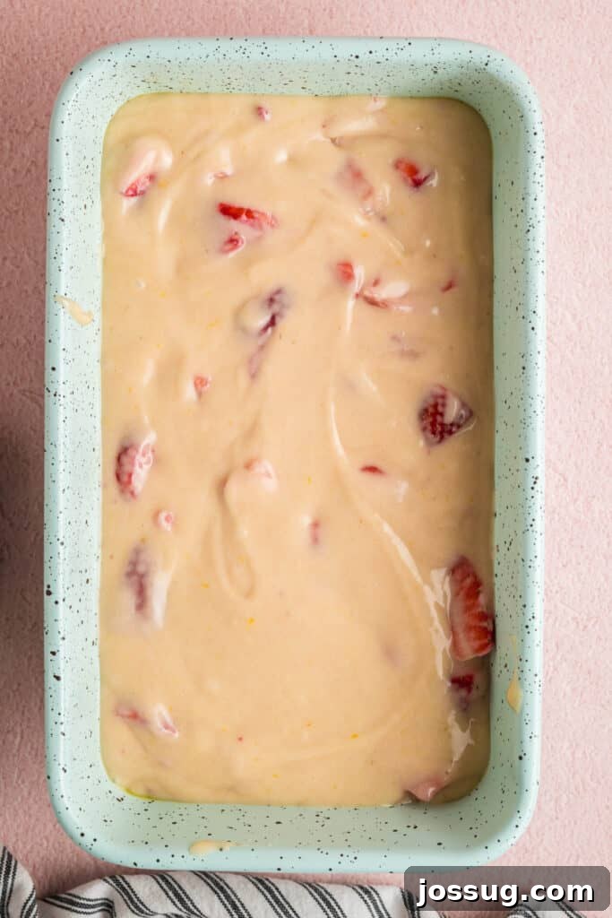 Sweet Strawberry Loaf 14 A close-up view of the strawberry bread batter carefully poured into a speckled loaf pan, with a smooth surface ready for the oven.