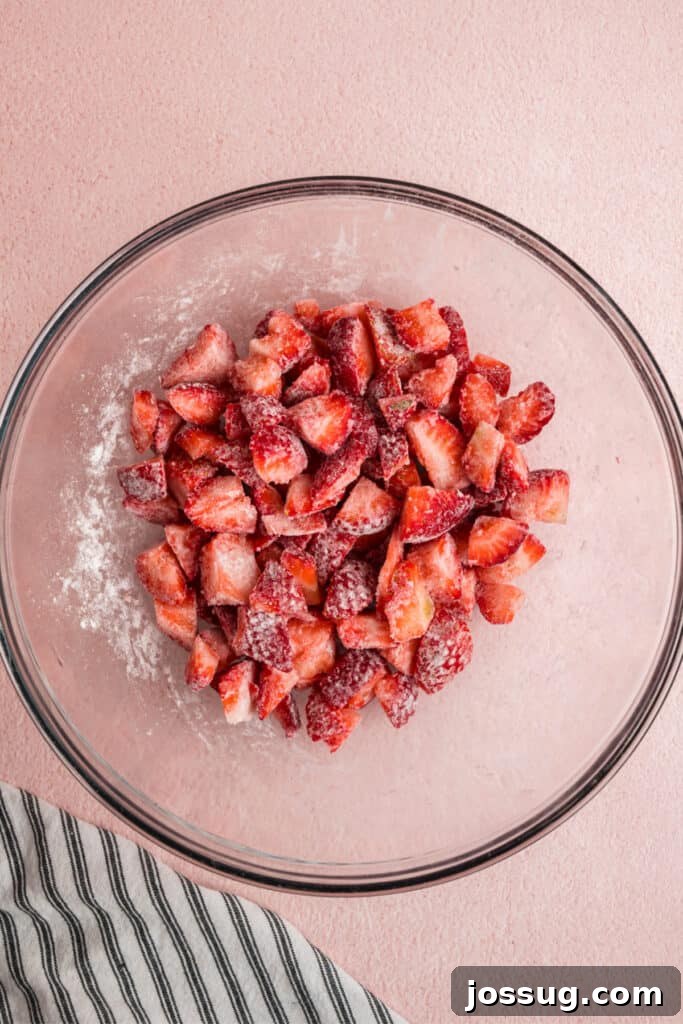 Sweet Strawberry Loaf 5 Close-up of flour-dusted strawberries in a bowl, showing how they are evenly coated to prevent sinking during baking.