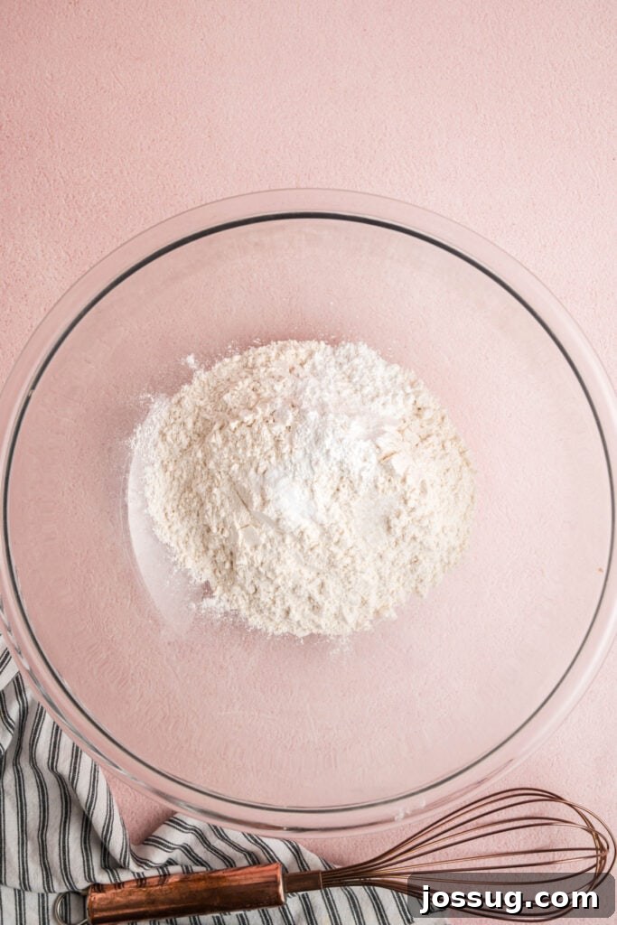 Sweet Strawberry Loaf 6 Dry ingredients, including all-purpose flour, baking powder, baking soda, and salt, are measured and placed in a large glass mixing bowl.