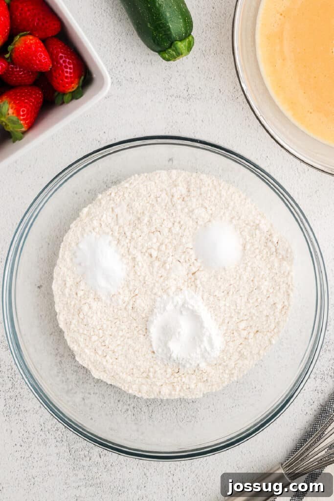 A separate clear bowl holds the perfectly measured dry ingredients: all-purpose flour, baking powder, baking soda, and salt, ready to be whisked together.