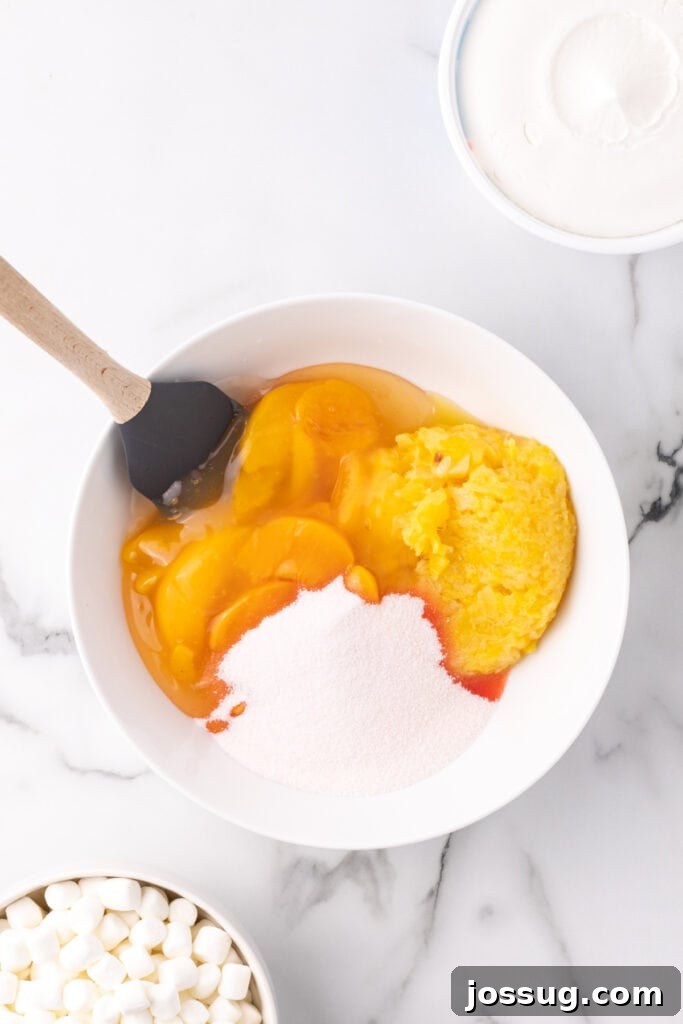 Bowl with peach pie filling, crushed pineapple, and peach gelatin being mixed together.