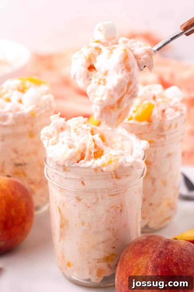 Spoonful of peach fluff salad being lifted from a jar with more jars in view, ready to be enjoyed.