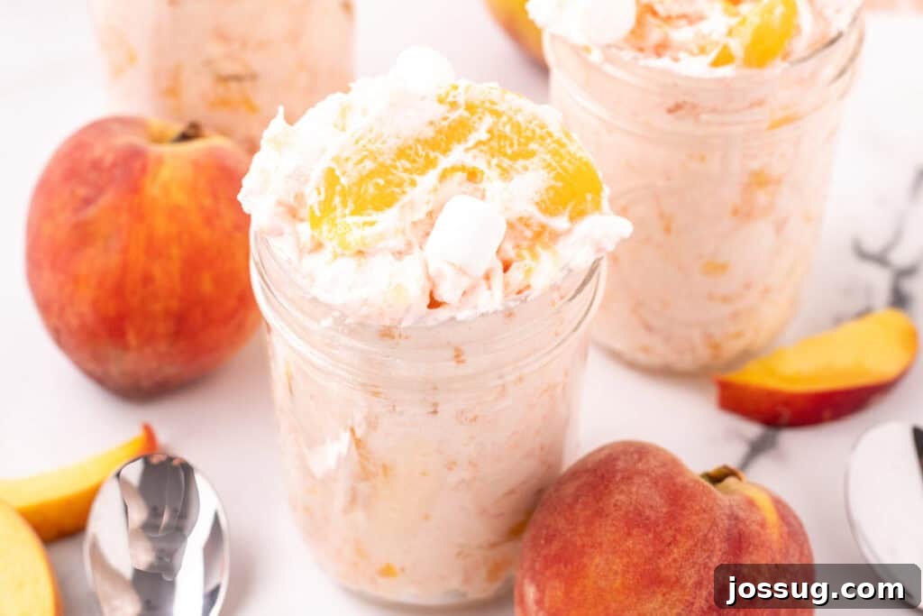 Close-up of peach fluff salad in a mason jar with peaches and marshmallows, highlighting its tempting texture.