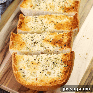 BEST Garlic Bread sliced on a cutting board, garnished with fresh parsley.