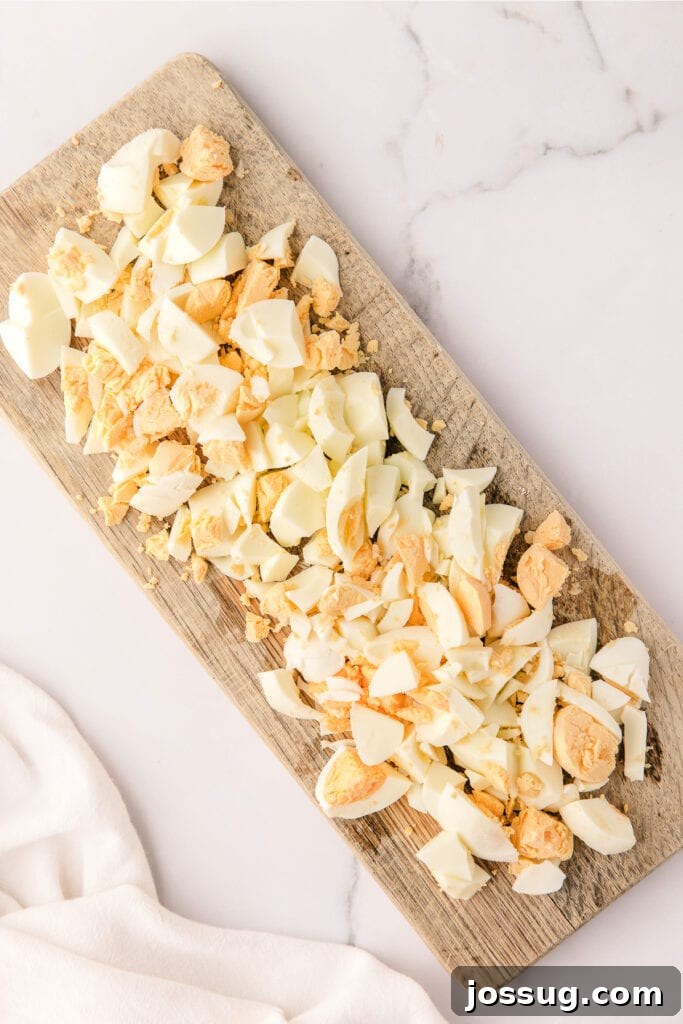Roughly chopped hard-boiled eggs on a cutting board, ready for mixing.