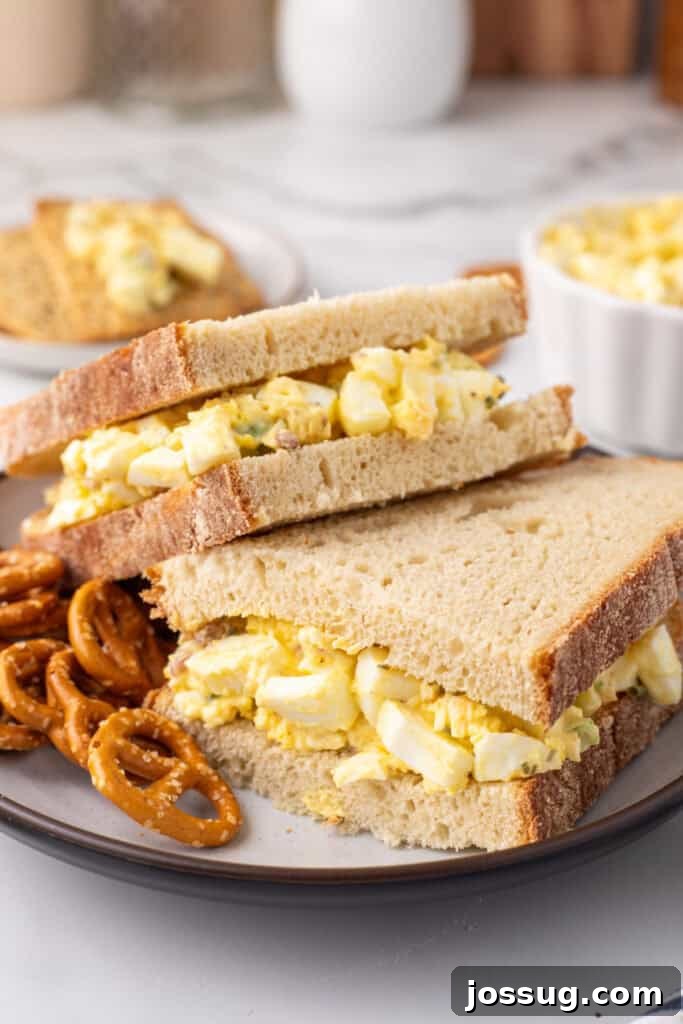 Golden Egg Salad 2 A delectable Million Dollar Egg Salad sandwich artfully presented on a white plate, showcasing its rich, creamy texture and vibrant ingredients.
