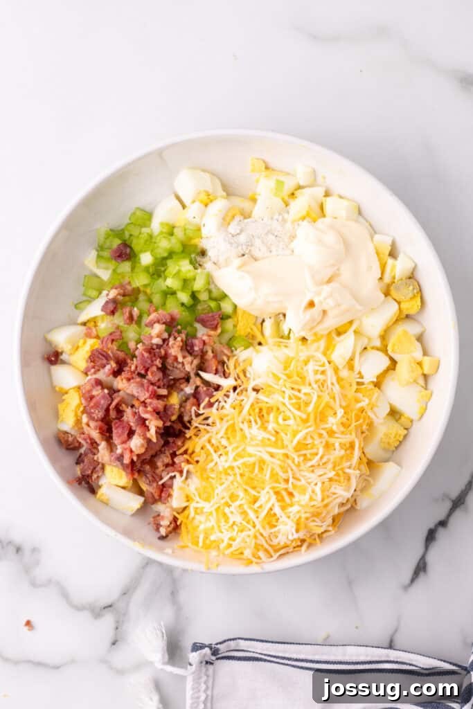 Golden Egg Salad 4 All the fresh ingredients for Million Dollar Egg Salad, including hard-boiled eggs, bacon, cheese, celery, and seasonings, laid out in bowls before mixing.