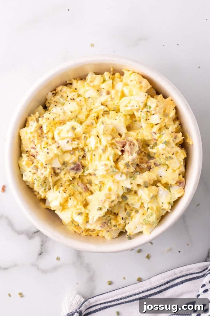 Golden Egg Salad 5 The Million Dollar Egg Salad ingredients beautifully mixed in a bowl, showcasing the creamy texture and delicious chunks of bacon, eggs, and cheese.