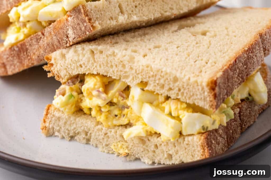Golden Egg Salad 7 A mouth-watering close-up of Million Dollar Egg Salad piled high on a slice of fresh bread, highlighting its rich, creamy texture and generous bacon and cheese bits.