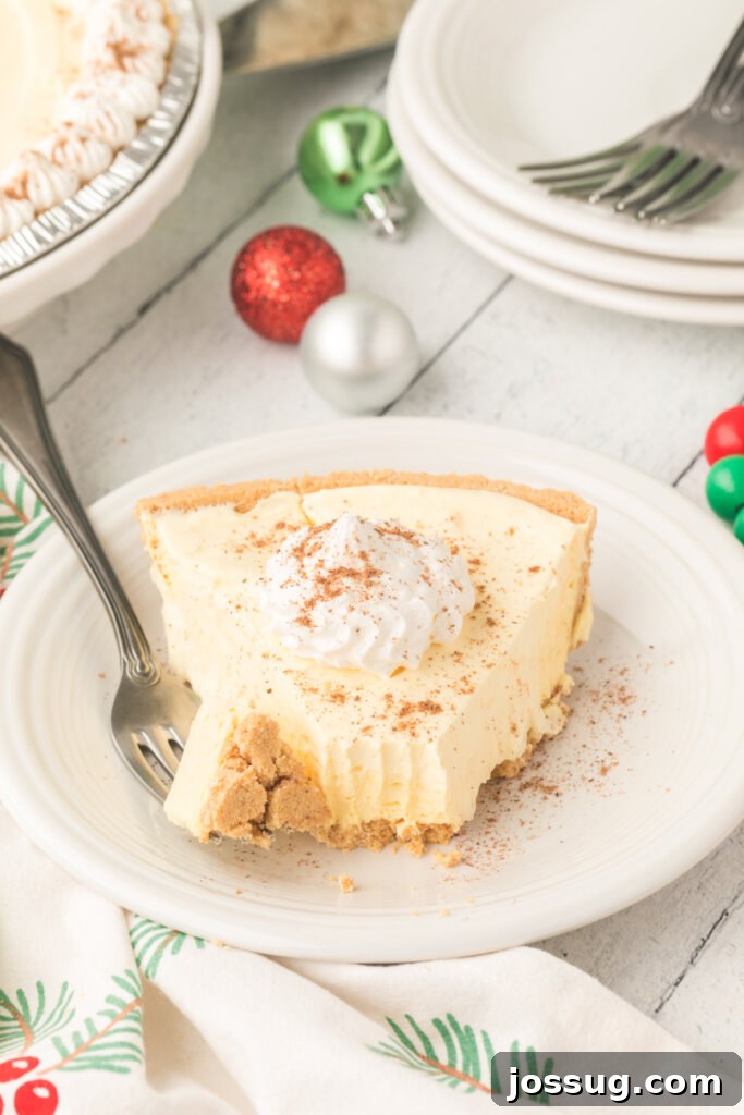 Dreamy No-Bake Eggnog Pie 4 A close-up shot of a slice of eggnog pie on a plate, with a bite taken out and a fork resting beside it, highlighting its creamy texture.