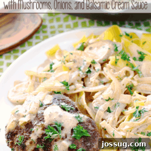 Italian Beef Patties with Mushrooms, Onions, and Balsamic Cream Sauce served over pasta on a white plate, garnished with fresh parsley.