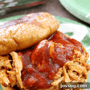 Pulled Pork BBQ Sandwiches 2 Slow Cooker BBQ Pulled Pork Sandwich close up on a plate with the top off.