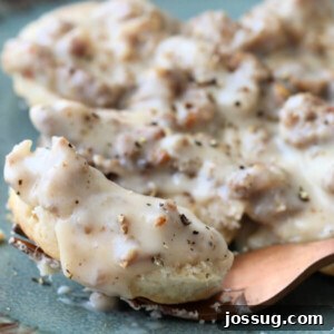closeup of sausage gravy over biscuits on a fork