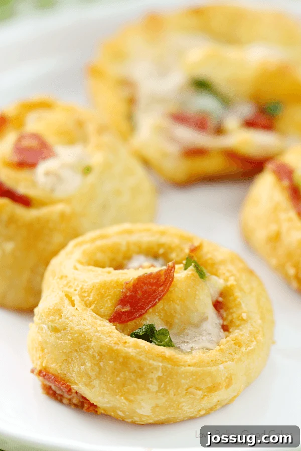 Golden-brown Pizza Pinwheels on a pristine white plate, with a detailed close-up shot highlighting their savory texture and melted cheese.