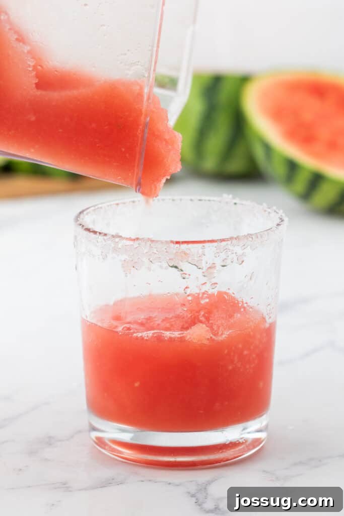Crimson Wave Margarita 10 Blended watermelon margarita being smoothly poured from a blender into a salt-rimmed glass, ready for serving