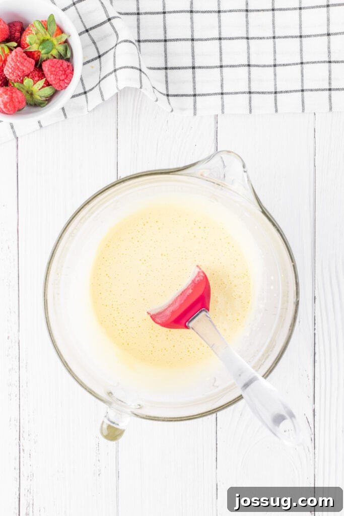 Creamy Three Milk Dream 4 An overhead shot showcasing two distinct glass bowls, one filled with pristine egg whites and the other with rich egg yolks, perfectly separated and ready for mixing to create the Tres Leches cake.