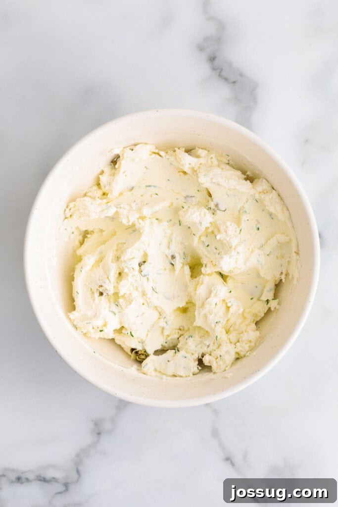 Dill and caper cream cheese mixture fully blended in a white bowl.