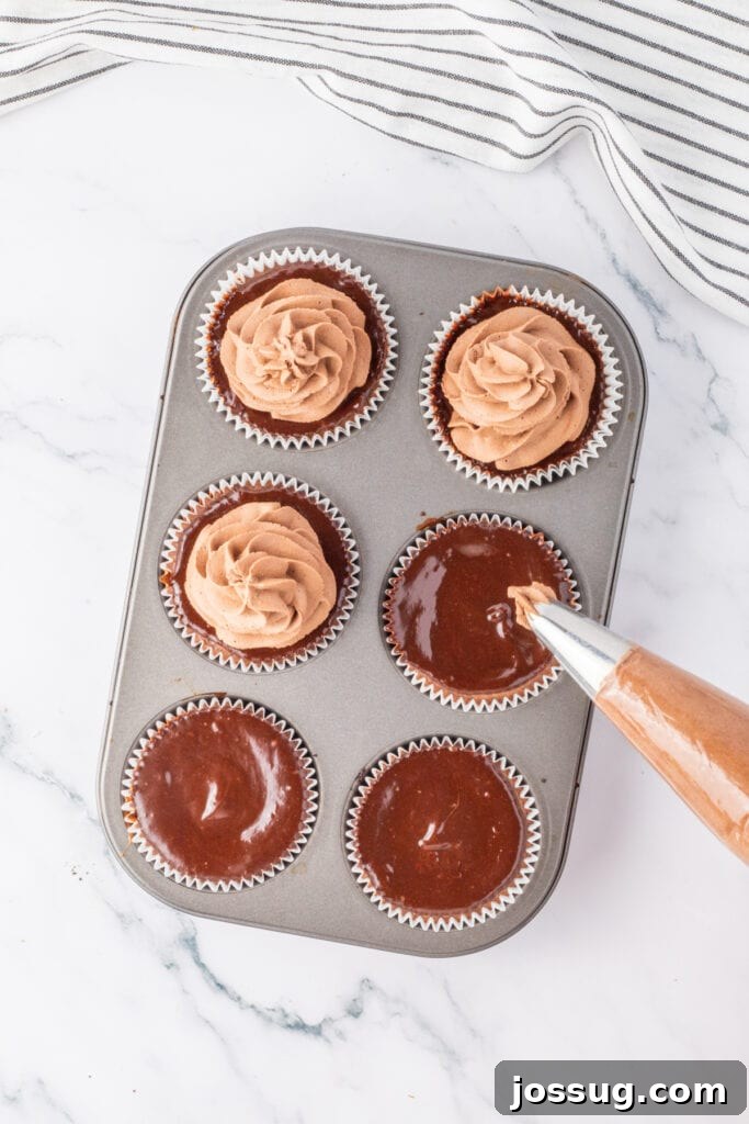 Piping chocolate whipped cream over mini chocolate cheesecakes in a muffin pan