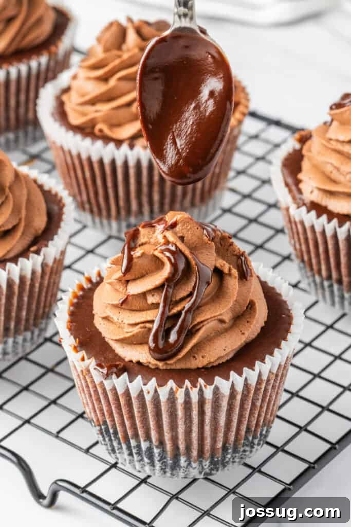 Spoon drizzling ganache over mini chocolate cheesecakes with piped frosting