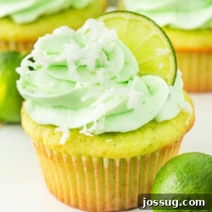 Bright and fluffy coconut lime cupcake with green frosting, lime slice, and shredded coconut on top